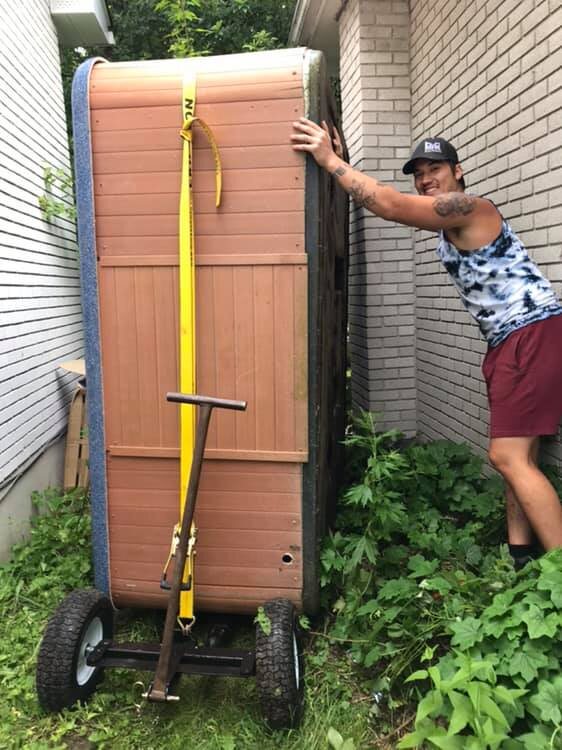 Hot tub being moved through a narrow side-yard path